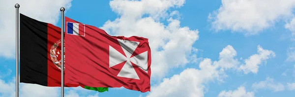 Afganistán y Wallis Y la bandera de Futuna ondeando en el viento contra el cielo azul nublado blanco juntos. Concepto diplomático, relaciones internacionales . — Foto de Stock