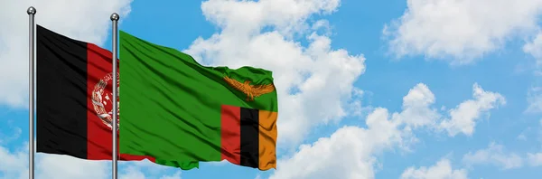 Bandera de Afganistán y Zambia ondeando en el viento contra el cielo azul nublado blanco juntos. Concepto diplomático, relaciones internacionales . — Foto de Stock