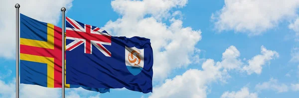 Aland Islands et le drapeau d'Anguilla agitant dans le vent contre ciel bleu nuageux blanc ensemble. Concept de diplomatie, relations internationales . — Photo