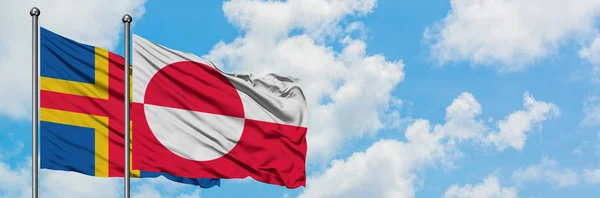 Alandské ostrovy a Grónská vlajka mávali ve větru proti bíle zatažené modré obloze. Diplomacie, mezinárodní vztahy. — Stock fotografie
