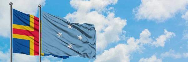 Aland Islands and Micronesia flag waving in the wind against white cloudy blue sky together. Diplomacy concept, international relations. — Stock Photo, Image