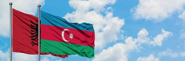 Bandera de Albania y Azerbaiyán ondeando en el viento contra el cielo azul nublado blanco juntos. Concepto diplomático, relaciones internacionales . — Foto de Stock