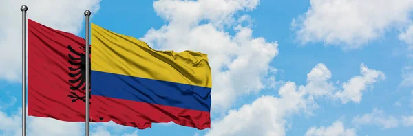 Bandera de Albania y Colombia ondeando en el viento contra el cielo azul nublado blanco juntos. Concepto diplomático, relaciones internacionales . — Foto de Stock