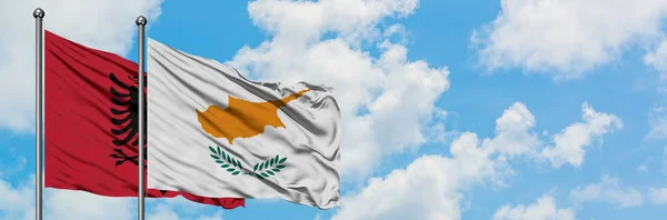 Drapeau de l'Albanie et de Chypre agitant dans le vent contre ciel bleu nuageux blanc ensemble. Concept de diplomatie, relations internationales . — Photo