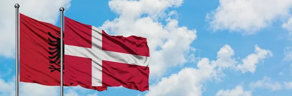 Albanien och Danmark sjunker vifta i vinden mot vit grumlig blå himmel tillsammans. Diplomatisk koncept, internationella relationer. — Stockfoto