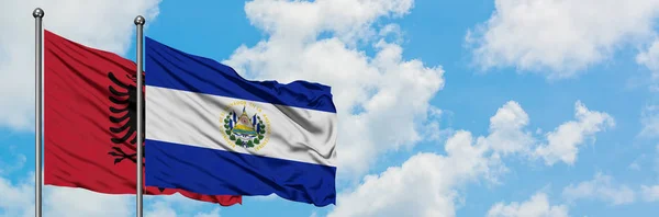 Albanien und El Salvador schwenken gemeinsam die Flagge im Wind vor dem wolkenverhangenen blauen Himmel. Diplomatie-Konzept, internationale Beziehungen. — Stockfoto