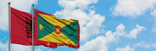 Albania and Grenada flag waving in the wind against white cloudy blue sky together. Diplomacy concept, international relations. — Stock Photo, Image