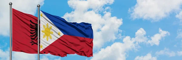 阿尔巴尼亚和菲律宾国旗在风中飘扬，白云蓝天相聚。外交概念、国际关系. — 图库照片