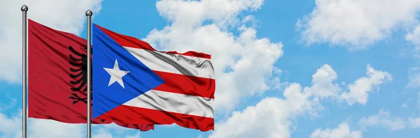 Arnavutluk ve Porto Riko bayrağı birlikte beyaz bulutlu mavi gökyüzüne karşı rüzgarda sallayarak. Diplomasi kavramı, uluslararası ilişkiler. — Stok fotoğraf