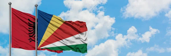 Albanië en de Seychellen vlag zwaaiende in de wind tegen witte bewolkte blauwe hemel samen. Diplomatie concept, internationale betrekkingen. — Stockfoto