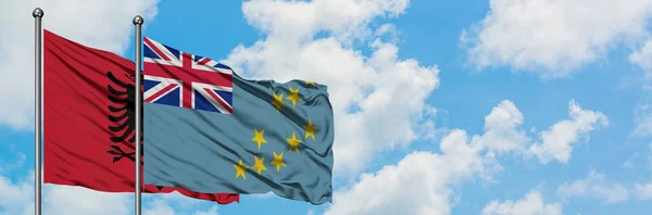 Bandera de Albania y Tuvalu ondeando en el viento contra el cielo azul nublado blanco juntos. Concepto diplomático, relaciones internacionales . — Foto de Stock
