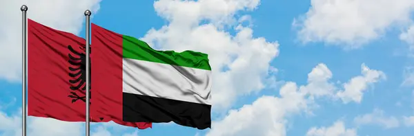 Bandera de Albania y Emiratos Árabes Unidos ondeando en el viento contra el cielo azul nublado blanco juntos. Concepto diplomático, relaciones internacionales . — Foto de Stock