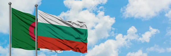 Bandera de Argelia y Bulgaria ondeando en el viento contra el cielo azul nublado blanco juntos. Concepto diplomático, relaciones internacionales . — Foto de Stock