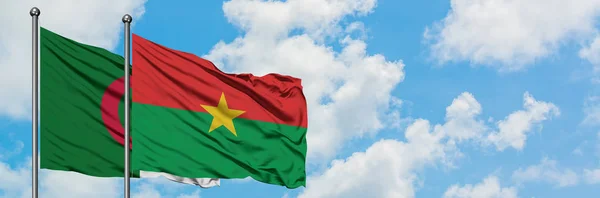 Argelia y Burkina Faso ondeando en el viento contra el cielo azul nublado blanco juntos. Concepto diplomático, relaciones internacionales . — Foto de Stock