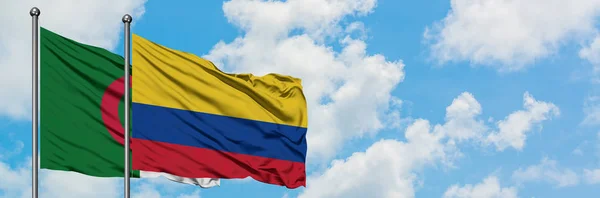 Bandera de Argelia y Colombia ondeando en el viento contra el cielo azul nublado blanco juntos. Concepto diplomático, relaciones internacionales . — Foto de Stock