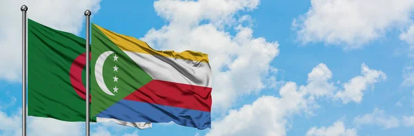 Bandera de Argelia y Comoras ondeando en el viento contra el cielo azul nublado blanco juntos. Concepto diplomático, relaciones internacionales . — Foto de Stock