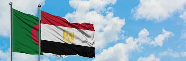 Bandera de Argelia y Egipto ondeando en el viento contra el cielo azul nublado blanco juntos. Concepto diplomático, relaciones internacionales. — Foto de Stock