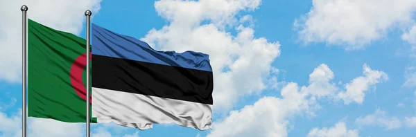 Bandera de Argelia y Estonia ondeando en el viento contra el cielo azul nublado blanco juntos. Concepto diplomático, relaciones internacionales . — Foto de Stock