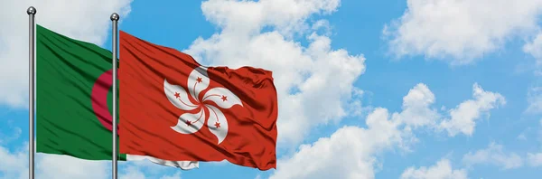 Bandera de Argelia y Hong Kong ondeando en el viento contra el cielo azul nublado blanco juntos. Concepto diplomático, relaciones internacionales . — Foto de Stock