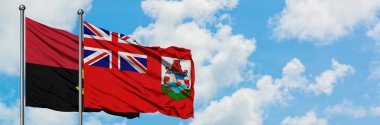 Angola ve Bermuda bayrağı birlikte beyaz bulutlu mavi gökyüzüne karşı rüzgarda sallayarak. Diplomasi kavramı, uluslararası ilişkiler.