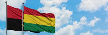 Angola ve Bolivya bayrağı birlikte beyaz bulutlu mavi gökyüzüne karşı rüzgarda sallayarak. Diplomasi kavramı, uluslararası ilişkiler.