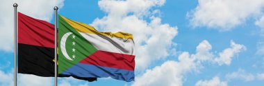 Angola ve Komorbayrağı birlikte beyaz bulutlu mavi gökyüzüne karşı rüzgarda sallayarak. Diplomasi kavramı, uluslararası ilişkiler.