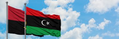 Angola ve Libya bayrağı birlikte beyaz bulutlu mavi gökyüzüne karşı rüzgarsal sallayarak. Diplomasi kavramı, uluslararası ilişkiler.