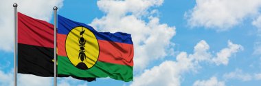 Angola ve Yeni Kaledonya bayrağı birlikte beyaz bulutlu mavi gökyüzüne karşı rüzgarda sallayarak. Diplomasi kavramı, uluslararası ilişkiler.