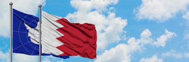 Antarktika ve Bahreyn bayrağı birlikte beyaz bulutlu mavi gökyüzüne karşı rüzgarda sallayarak. Diplomasi kavramı, uluslararası ilişkiler.