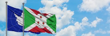 Antarktika ve Burundi bayrağı birlikte beyaz bulutlu mavi gökyüzüne karşı rüzgarda sallayarak. Diplomasi kavramı, uluslararası ilişkiler.