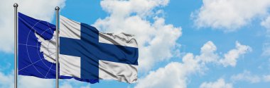 Antarktika ve Finlandiya bayrağı birlikte beyaz bulutlu mavi gökyüzüne karşı rüzgarda sallayarak. Diplomasi kavramı, uluslararası ilişkiler.