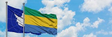 Antarktika ve Gabon bayrağı birlikte beyaz bulutlu mavi gökyüzüne karşı rüzgarda sallayarak. Diplomasi kavramı, uluslararası ilişkiler.