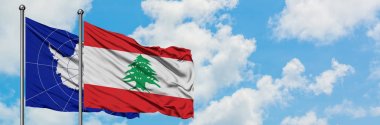 Antarktika ve Lübnan bayrağı birlikte beyaz bulutlu mavi gökyüzüne karşı rüzgarda sallayarak. Diplomasi kavramı, uluslararası ilişkiler.