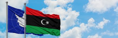 Antarktika ve Libya bayrağı birlikte beyaz bulutlu mavi gökyüzüne karşı rüzgarda sallayarak. Diplomasi kavramı, uluslararası ilişkiler.