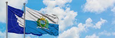 Antarktika ve San Marino bayrağı birlikte beyaz bulutlu mavi gökyüzüne karşı rüzgarda sallayarak. Diplomasi kavramı, uluslararası ilişkiler.