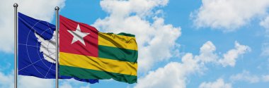 Antarktika ve Togo bayrağı birlikte beyaz bulutlu mavi gökyüzüne karşı rüzgarda sallayarak. Diplomasi kavramı, uluslararası ilişkiler.
