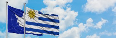 Antarktika ve Uruguay bayrağı birlikte beyaz bulutlu mavi gökyüzüne karşı rüzgarda sallayarak. Diplomasi kavramı, uluslararası ilişkiler.