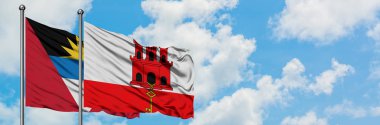 Antigua ve Barbuda Cebelitarık bayrağı ile birlikte beyaz bulutlu mavi gökyüzüne karşı rüzgarda sallayarak. Diplomasi kavramı, uluslararası ilişkiler.