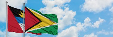 Antigua ve Guyana bayrağı ile Barbuda birlikte beyaz bulutlu mavi gökyüzüne karşı rüzgarda sallayarak. Diplomasi kavramı, uluslararası ilişkiler.