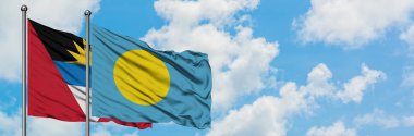 Antigua ve Barbuda Palau bayrağı ile birlikte beyaz bulutlu mavi gökyüzüne karşı rüzgarda sallayarak. Diplomasi kavramı, uluslararası ilişkiler.
