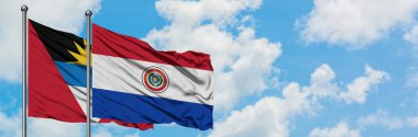 Antigua ve Barbuda Paraguay bayrağı ile birlikte beyaz bulutlu mavi gökyüzüne karşı rüzgarda sallayarak. Diplomasi kavramı, uluslararası ilişkiler.