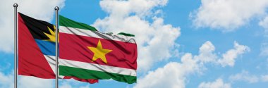 Antigua ve Barbuda surinam bayrağı ile birlikte beyaz bulutlu mavi gökyüzüne karşı rüzgarda sallayarak. Diplomasi kavramı, uluslararası ilişkiler.