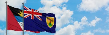 Antigua ve Barbuda ile Turks ve Caicos Adaları bayrağı birlikte beyaz bulutlu mavi gökyüzüne karşı rüzgarda sallayarak. Diplomasi kavramı, uluslararası ilişkiler.