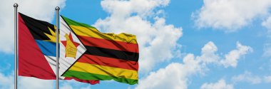 Antigua ve Barbuda Zimbabve bayrağı ile birlikte beyaz bulutlu mavi gökyüzüne karşı rüzgarda sallayarak. Diplomasi kavramı, uluslararası ilişkiler.