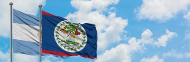 Arjantin ve Belize bayrağı birlikte beyaz bulutlu mavi gökyüzüne karşı rüzgarda sallayarak. Diplomasi kavramı, uluslararası ilişkiler.