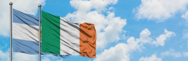 Arjantin ve İrlanda bayrağı birlikte beyaz bulutlu mavi gökyüzüne karşı rüzgarda sallayarak. Diplomasi kavramı, uluslararası ilişkiler.