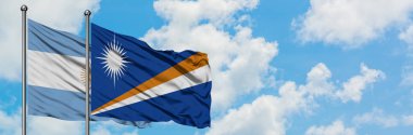 Arjantin ve Marshall Adaları bayrağı birlikte beyaz bulutlu mavi gökyüzüne karşı rüzgarda sallayarak. Diplomasi kavramı, uluslararası ilişkiler.