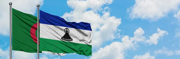 Argélia e Lesoto acenando com o vento contra o céu azul nublado branco juntos. Conceito de diplomacia, relações internacionais . — Fotografia de Stock