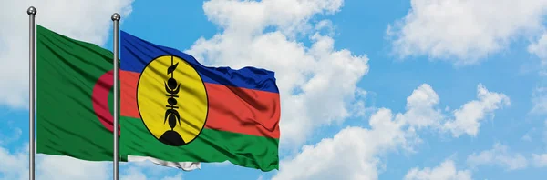 Bandera de Argelia y Nueva Caledonia ondeando en el viento contra el cielo azul nublado blanco juntos. Concepto diplomático, relaciones internacionales . — Foto de Stock