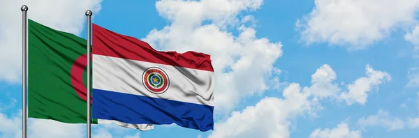 Bandera de Argelia y Paraguay ondeando en el viento contra el cielo azul nublado blanco juntos. Concepto diplomático, relaciones internacionales . — Foto de Stock